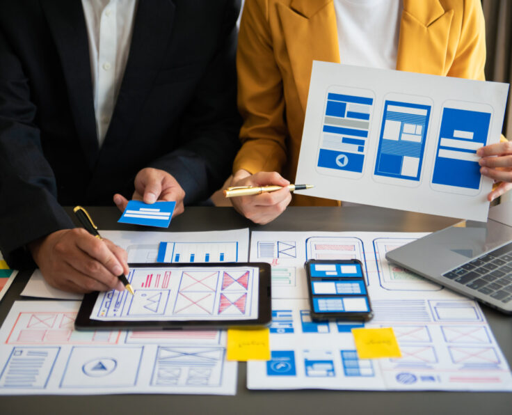 UX developer and ui designer brainstorming about mobile app interface wireframe design with customer breif and color code at modern office.